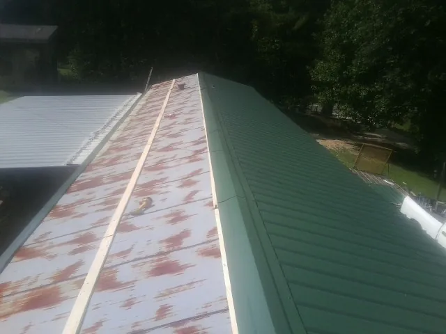 Old rusted panels beside newly installed green metal roofing — Wind Damage Roof Repair by Roofing Brothers in Mound Valley