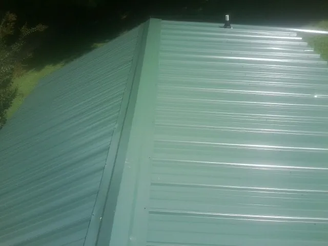 New green metal panels meeting at the ridge of a roof — Flat Roof Repair work by our crew in Mound Valley