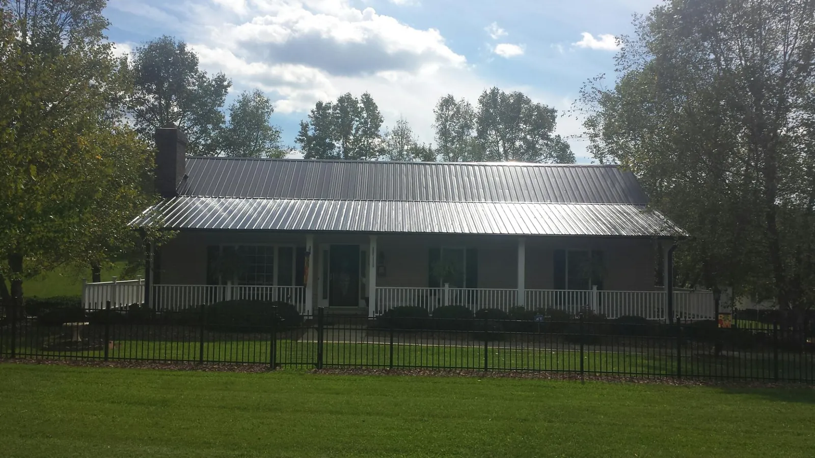 Gray metal roof on a brick ranch with a full width front porch — Gutter Guard Installation work by our crew in Mound Valley
