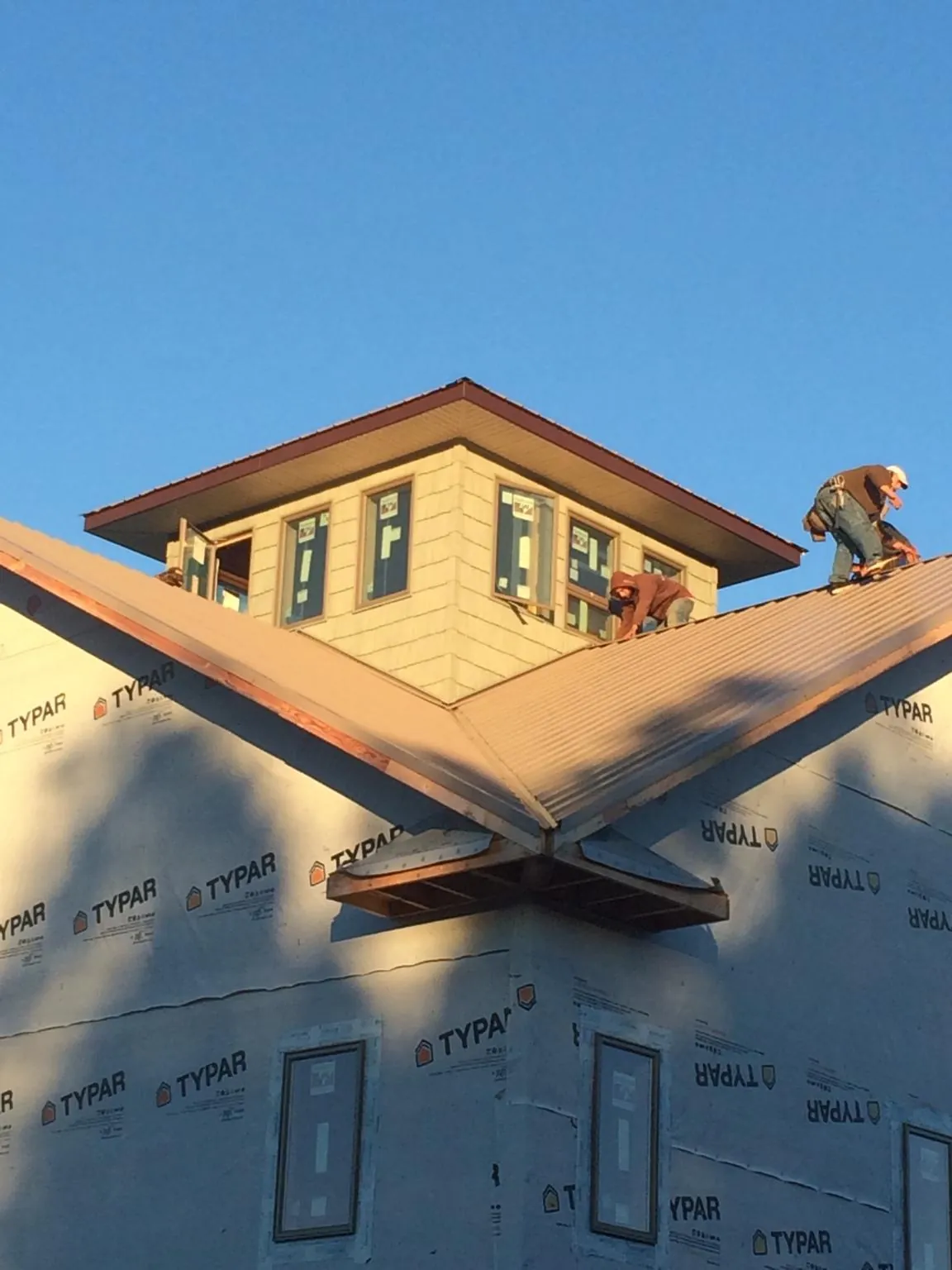 Roofers working around a rooftop cupola on a new metal roof at sunset — Roof Waterproofing in Mound Valley by Roofing Brothers